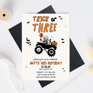 May include: Halloween-themed birthday invitation with the text "Trick or Three." The invitation features a skeleton driving a monster truck with a pumpkin and a balloon. The invitation includes the party details: date, time, location, and RSVP information.