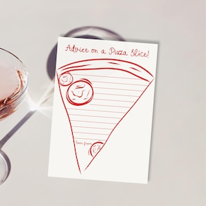 May include: A white card with a red pizza slice design and the text "Advice on a Pizza Slice!". The card has a lined interior for writing and the words "love from" at the bottom. A glass of pink liquid is in the background.