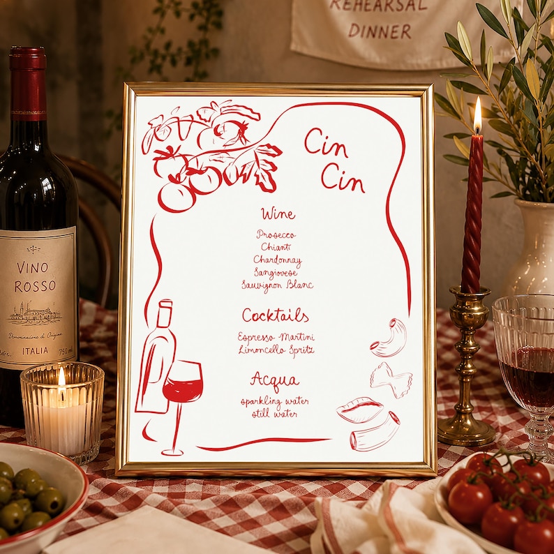 May include: A gold-framed menu sign featuring red line art illustrations of tomatoes, a wine bottle, a glass, and pasta shapes. The text reads Cin Cin, Wine, Prosecco, Chianti, Chardonnay, Sangiovese, Sauvignon Blanc, Cocktails, Espresso Martini, Limoncello Spritz, Acqua, sparkling water, and still water.