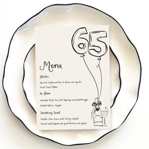May include: A black and white menu with the number 65 in balloon form at the top. The menu lists a starter, items to share, and something sweet. The text reads: "Menu, Starter, Spinach & feta and ham & cheese mini quiche, Fresh Fruit Platter, to Share, Avocado Toast Bar with Toppings and poached eggs, Smoked Salmon Bagels, Something Sweet, Vanilla Bean Scones with Berry Compote, French toast topped with fresh berries and syrup."