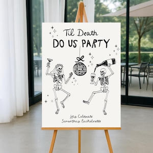 May include: A white sign on a wooden easel with the text "Til Death Do Us Party" and skeleton illustrations. One skeleton holds a glass, the other pours wine. The sign also says "Let's Celebrate Samantha's Bachelorette".
