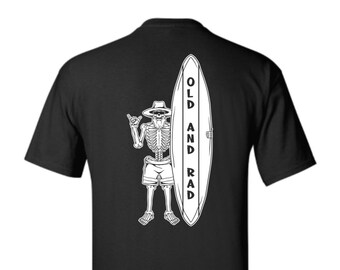 May include: Black t-shirt with a white skeleton surfer holding a surfboard that says "OLD AND RAD".