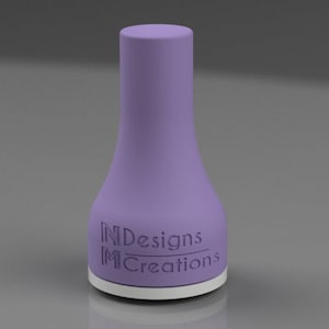 Pode incluir: Um tampão de garrafa roxo com o texto "INDesigns MCreations" gravado em relevo no lado.