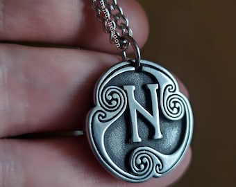 May include: Silver necklace with a pendant featuring the letter N in a Celtic knot design.