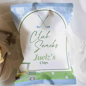 May include: A blue and green bag of crisps with a golf theme. The bag has a white label with the text "Club Snacks Juelz's Chips" and a graphic of two crossed golf clubs.