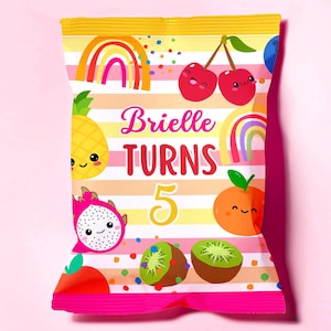 Könnte beinhalten: Ein farbenfroher Partybeutel mit einem rosa-gelb gestreiften Hintergrund. Der Beutel zeigt Illustrationen von lächelnden Früchten, Regenbogen und den Text "Brielle TURNS 5". Der Beutel ist oben versiegelt und hat einen rosa Boden.