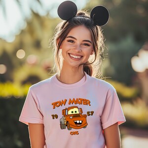 a woman wearing a pink shirt with a mickey mouse ears on her head