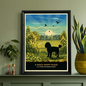 May include: A framed art print depicting a black dog silhouette in a park scene. The artwork showcases a colourful sky, trees, and the text "A DOG'S HAPPY PLACE IS A PARK OR GREEN SPACE". The print is displayed on a shelf with plants.