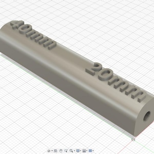 Può includere: Un oggetto cilindrico grigio chiaro con le scritte "40mm" e "20mm" in rilievo sulla superficie. L'oggetto ha un'estremità arrotondata con un piccolo foro. Lo sfondo è una griglia.