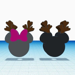 May include: Two three-dimensional mouse-shaped ornaments with brown reindeer antlers. The left ornament is gray with a bright magenta bow between the antlers. The right ornament is solid black. Both feature a circular hole at the bottom base.