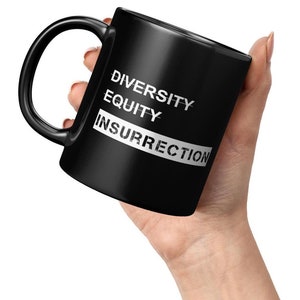 May include: Black coffee mug with the words "Diversity Equity Insurrection" printed in white.