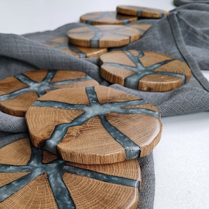 May include: Set of six wooden coasters with a gray resin inlay. The coasters have a natural wood grain pattern and are circular in shape.