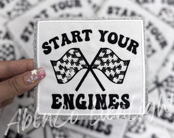 Puede incluir: Parche blanco para planchar con texto negro y diseño de bandera a cuadros. El texto dice "Start Your Engines".