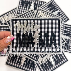 May include: A black and white checkered fabric patch with silver glitter lettering that reads "Moto Mama" with a silver lightning bolt.