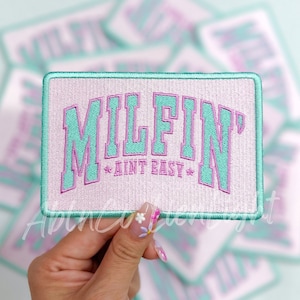 May include: A pink and green embroidered patch with the text "MILFIN' AINT EASY" in a retro font.