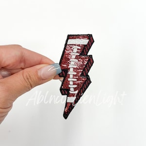 May include: Red and white football-themed lightning bolt iron-on patch.