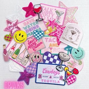 May include: A collection of colorful iron-on patches featuring various drink-themed designs, including cocktails, wine glasses, and text like "Talk Dirty to Me", "Save Water Drink More", "Spicy Marg Queen", "Taco and Margs", "Tini Time", and "Cowboys & Tequila".