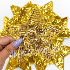 May include: A pack of gold sequin star patches. The stars are about 3 inches wide and have a shiny, sparkly finish.