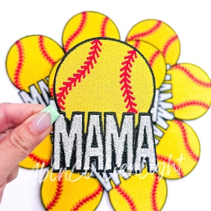 May include: A yellow softball with red stitching and the word "MAMA" embroidered in white. The softball is surrounded by other yellow softballs with red stitching.