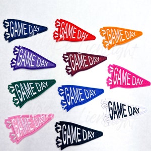 May include: Ten felt pennant flags with the text "GAME DAY" in white lettering. The flags are in various colors including red, orange, yellow, green, blue, purple, pink, and black.