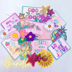 May include: A collection of colorful iron-on patches with various religious and inspirational messages, including "God is Good", "Have a Good Day", "Faith", "Created with a Purpose", "Love Like Jesus", "Make Heaven Crowded", and "He Freed". The patches are decorated with sequins, glitter, and embroidery.