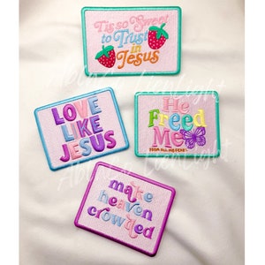 May include: Four embroidered iron-on patches with pink backgrounds and colorful text. The patches feature the phrases "Tis so Sweet to Trust in Jesus", "Love Like Jesus", "He Freed Me From All My Fears", and "Make Heaven Crowded".