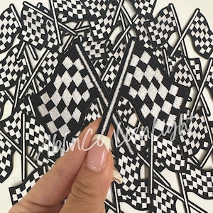 May include: A pile of black and white checkered flags with a white border. The flags are sewn and have a stick attached to the back.
