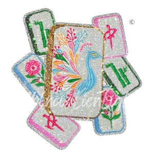 May include: A collection of sequined, rectangular accessories with embroidered designs. The central piece features a blue peacock with a colorful tail. Other pieces display floral and bamboo motifs, and Chinese characters. A gold chain is attached.