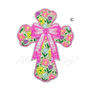 May include: Embroidered cross with a pink bow and floral design. The cross is adorned with pink, yellow, and purple flowers, and outlined with silver sequins. The design is on a white background.
