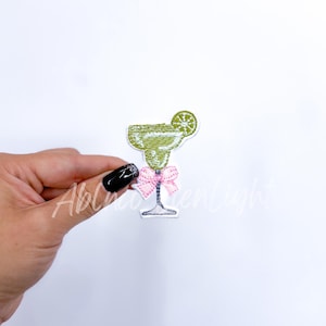 May include: Green embroidered iron-on patch of a margarita glass with a lime wedge and a pink bow.