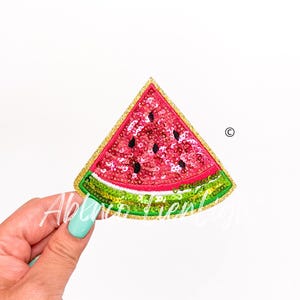 May include: A red and green watermelon slice patch with gold glitter trim. The watermelon is made of sequins and is a fun and colorful patch.
