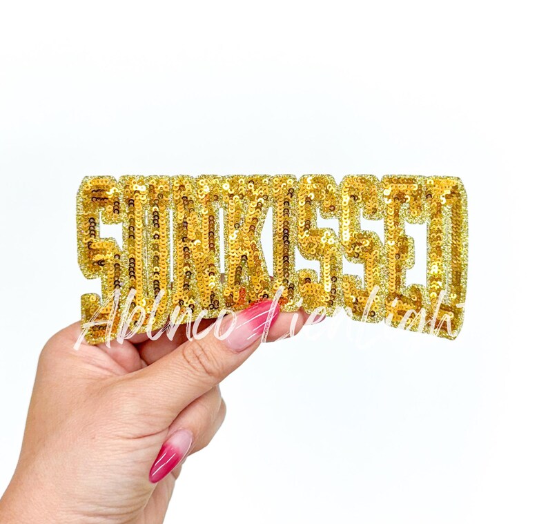 May include: Gold sequined iron-on patch that says "Slay" in all capital letters.