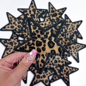 May include: A set of eight leopard print star-shaped patches with black trim. The patches are made of a soft, plush fabric and are perfect for adding a touch of whimsy to any project.
