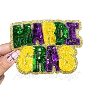 May include: A Mardi Gras themed patch with the words "MARDI GRAS" in green, purple, and yellow sequins. The patch has a gold glitter border and is held up by a hand.