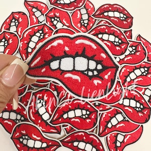 May include: A pile of red embroidered iron-on patches featuring a cartoon mouth with white teeth.