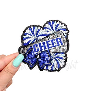 May include: Blue and silver sequined iron-on patch with a cheerleading megaphone and pom-poms. The megaphone has the word "CHEER" on it.