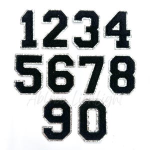May include: Ten black iron-on patches with silver glitter trim, featuring the numbers 1 through 10.