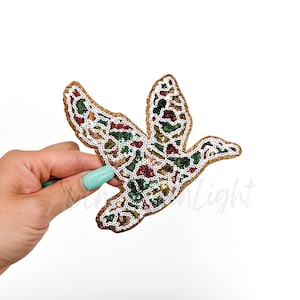 May include: A gold, green, red, and white sequined iron-on patch in the shape of a flying bird.