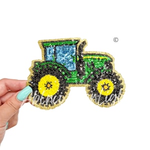 May include: Green and black tractor applique with gold sequins. The tractor has a blue window and yellow wheels.