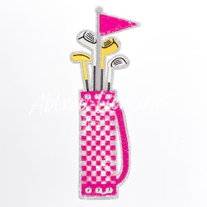 May include: A pink and white checkered golf bag with a pink flag and yellow and white golf clubs sticking out of the top.