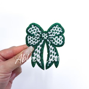 May include: Green and white checkered bow with glitter, iron-on patch.