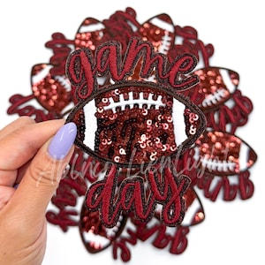May include: A set of red and white iron-on patches featuring a football design and the text "game day".