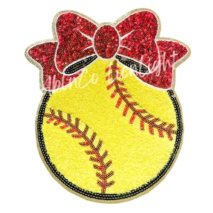 May include: A yellow and red softball with a red bow on top. The softball and bow are made of sequins.