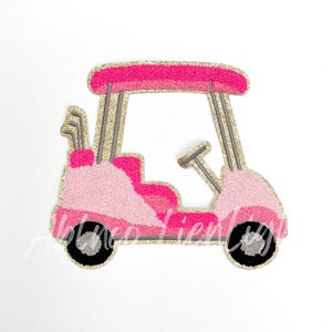 May include: A pink and gold glitter golf cart with a gray steering wheel and golf clubs in the back.