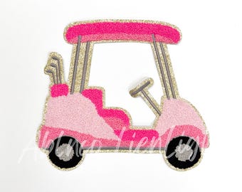 May include: A pink and gold glitter golf cart with a gray steering wheel and golf clubs in the back.