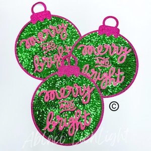 May include: Three green and pink Christmas ornaments with the words "merry and bright" written in pink on each ornament.