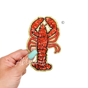 May include: Red and gold embroidered lobster patch with sequins.