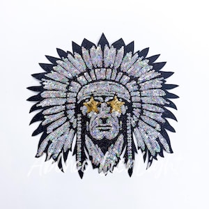 May include: A black and silver sequined Native American headdress with a face in the center. The face has gold star-shaped eyes.