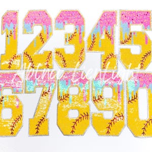 May include: A set of glittery yellow numbers, 0-9, with pink and blue dripping accents. Each number features a baseball stitch design. The numbers are outlined in silver glitter, creating a playful and decorative effect.