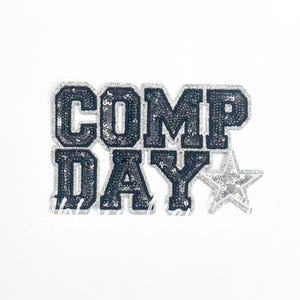 May include: A black and silver sequined iron-on patch with the text "COMP DAY" and a silver star.